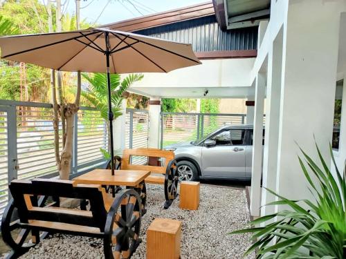 a patio with a table and an umbrella and a car at 3Bed&Bath family friendly house in Davao City