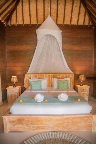 a bedroom with a large bed with two lamps at Villa Tahid in Gili Air