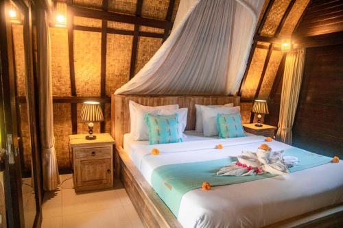 a bedroom with a bed with two tables and two lamps at Villa Tahid in Gili Air