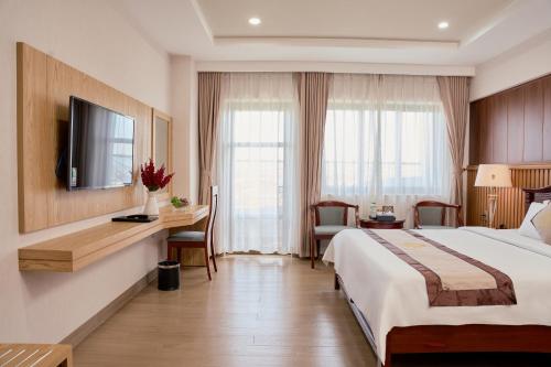 Una habitación de hotel con una cama, un escritorio y un televisor. en Khách Sạn Rex An Nhơn, en Hòa Nghi