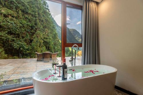 a bath tub in a room with a large window at Huagu Jianzhu Guesthouse (Zhangjiajie National Forest Park Branch) in Jiawan