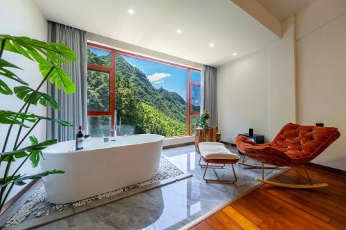 a bathroom with a tub and a chair and a large window at Huagu Jianzhu Guesthouse (Zhangjiajie National Forest Park Branch) in Jiawan