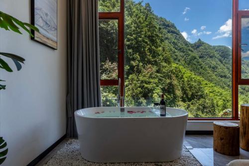 a bath tub in a room with a large window at Huagu Jianzhu Guesthouse (Zhangjiajie National Forest Park Branch) in Jiawan