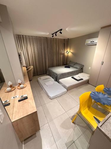 a bedroom with a bed and a table and a yellow chair at Flat localizado a 200m Shopping Recife, bem Perto da Praia de Boa Viagem e com Wi-Fi 400Mbps in Recife