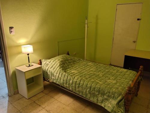 a bedroom with a bed and a lamp on a table at Casa del Arbol in San Fernando del Valle de Catamarca