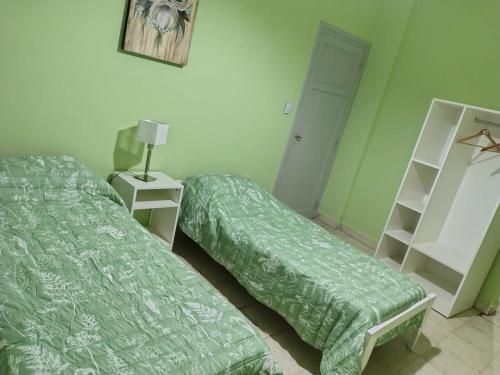 two beds in a room with green walls at Casa del Arbol in San Fernando del Valle de Catamarca