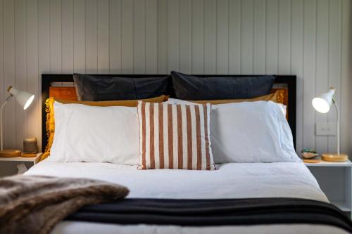a bed with two pillows and two lamps on it at Creekside at Kūaotunu in Matarangi