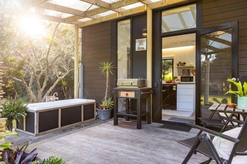 a screened in porch with a tub and a kitchen at Creekside at Kūaotunu in Matarangi