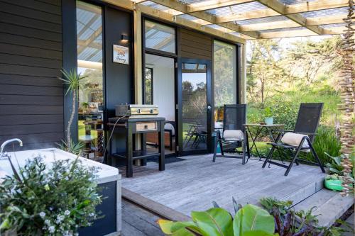 a screened in porch with chairs and a table at Creekside at Kūaotunu in Matarangi