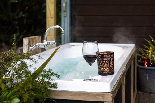 a glass of wine sitting in a bathtub with a glass of wine at Creekside at Kūaotunu in Matarangi