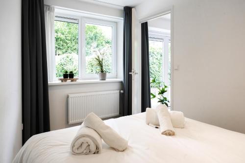 a white bed with two pillows and two windows at Child-friendly With Equipped Kitchen, Gerard in Eindhoven