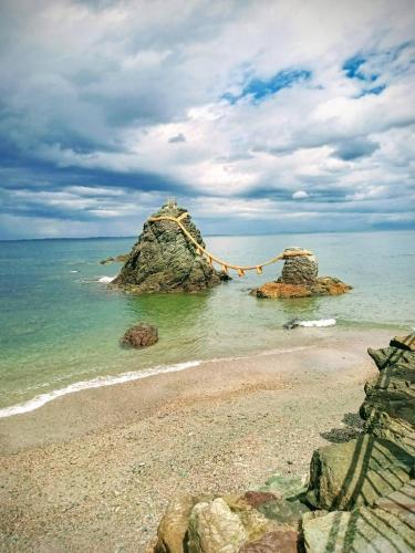 a beach with a rock in the water at Nagata House in Ise