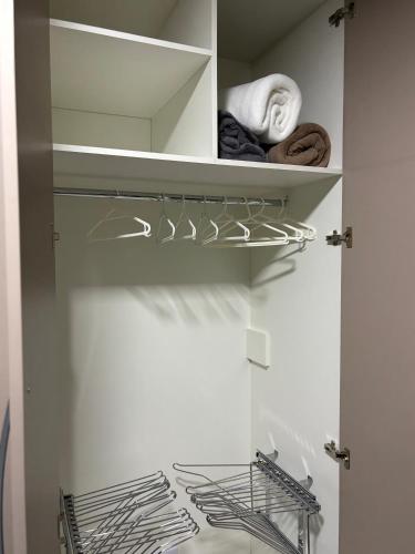 a closet with white walls and shelves with towels at Casa Confortável 03 Quartos Com Suite, Churrasqueira, Banheira e Garagem in Curitiba