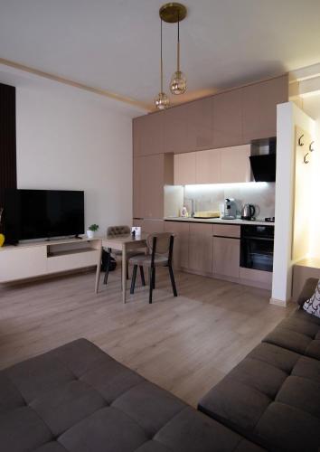 a living room with a table and a kitchen at Gratia Apartments in Kumanovo