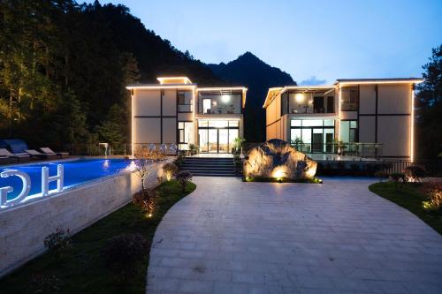 a large house with a swimming pool in front of it at Huagu Jianzhu Guesthouse (Zhangjiajie National Forest Park Branch) in Jiawan