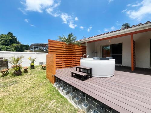 una terrazza in legno con vasca idromassaggio all'interno di una casa. di ぬちゆい a Nakijin