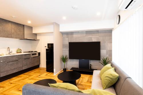 a living room with a couch and a flat screen tv at Amp Flat TFK西新駅前 in Fukuoka