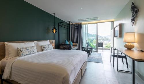 a bedroom with a large white bed and a desk at Fusion Suites Phuket Patong in Patong Beach