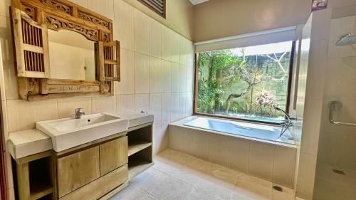 ジンバランにあるBukawa Lodge Jimbaranの洗面台、浴槽、窓のあるバスルーム