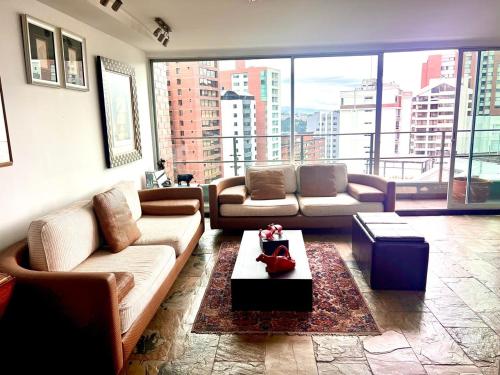 a living room with couches and a large window at Penthouse con vista, Zona Top in Quito