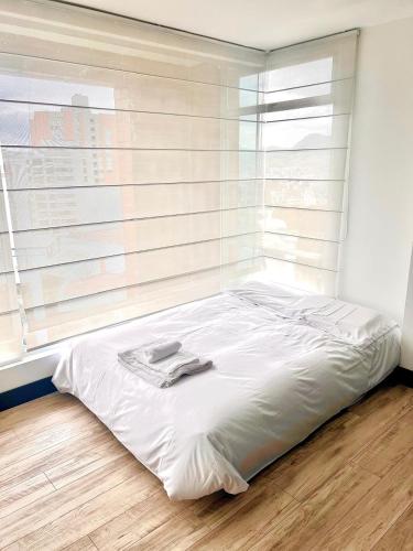a white bed in a room with a window at Penthouse con vista, Zona Top in Quito