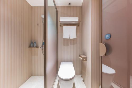 a small bathroom with a toilet and a shower at Hanting Hotel Beijing Guang'anmen in Beijing