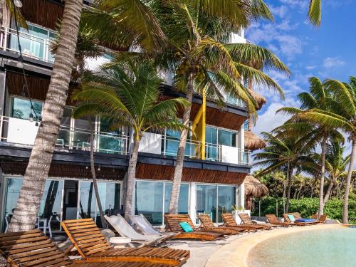 a resort with chairs and a swimming pool and palm trees at Angelina 28 Beachfront and Family Apartments - Modern and Relaxing Long Stays - 20 min from Cancun Airport in Puerto Morelos