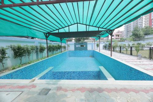Una gran piscina con cubierta azul en un edificio. en The Leela's Farm, en Gurgaon