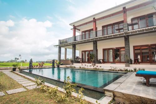 a villa with a swimming pool in front of a building at Villa Popolan and Guest House in Ubud
