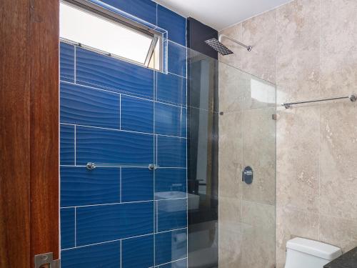 a bathroom with a glass shower with blue tiles at Angelina 28 Beachfront and Family Apartments - Modern and Relaxing Long Stays - 20 min from Cancun Airport in Puerto Morelos