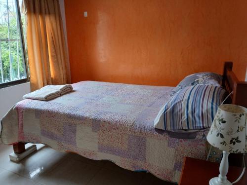 a bedroom with a bed and a lamp and a window at Casa Ambrosía Eje Cafetero in Pereira