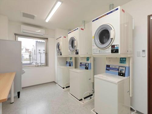 a laundry room with three washing machines and a window at A&Bee HOTEL in Oita