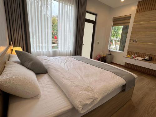 a bedroom with a large bed with white sheets and pillows at Mộc Sơn Homestay in Mộc Châu
