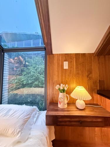 a bedroom with a bed and a table with a lamp at Homestay My Ny Đà Lạt in Khu Chi Lăng