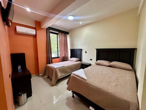 a bedroom with two beds and a window at Hotel San Isidro in Malacatán