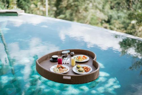 een dienblad met eten bovenop een zwembad bij Umah Bali Kuno Villa in Tampaksiring