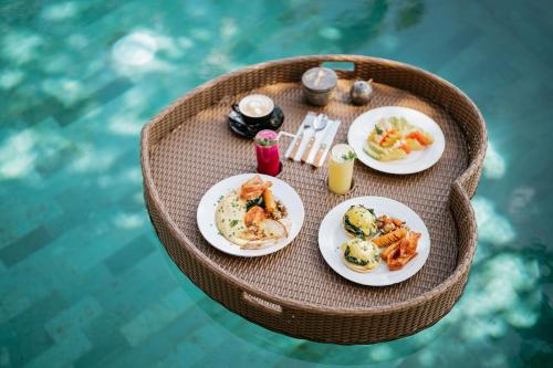 een tafel met borden eten naast een zwembad bij Umah Bali Kuno Villa in Tampaksiring