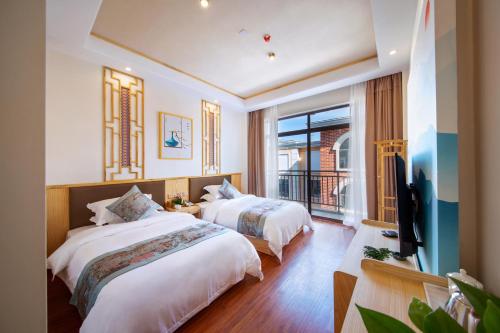 a bedroom with two beds and a balcony at Airport Boutique Hotel-Free pick-up in Zhangjiajie