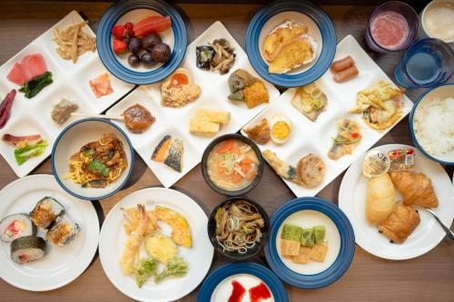 松本市にあるTabino Hotel lit Matsumoto Milky white Onsenのさまざまな食べ物が盛られた皿が並んだテーブル