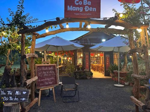 a restaurant with an arch with a sign and umbrellas at Cô Ba Homestay Măng Đen in Kon Von Kla