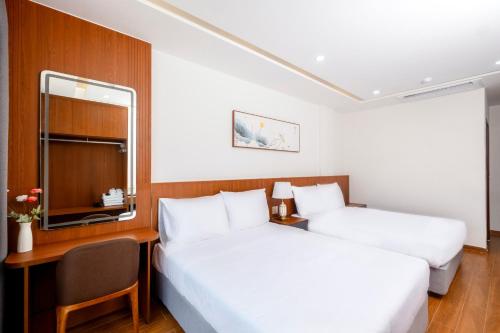a hotel room with two beds and a desk and a mirror at Great Hotel Phú Quốc in Phu Quoc