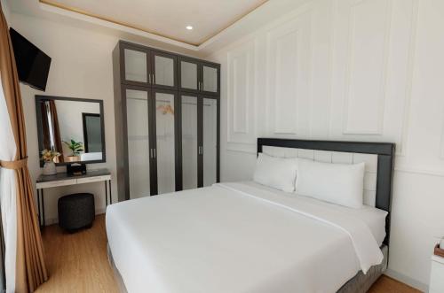 a bedroom with a white bed and a mirror at Marina Villa 1 in Yogyakarta