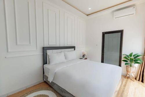 a white bedroom with a large white bed in it at Marina Villa 1 in Yogyakarta