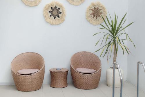 four rattan chairs and a plant against a wall at Marina Villa 1 in Yogyakarta
