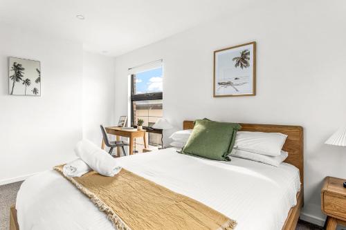 a bedroom with a bed with white sheets and a window at Station & Surf 3BR Wollongong Townhouse in Wollongong