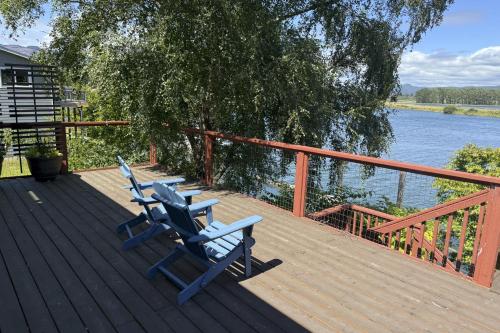 two blue chairs sitting on a deck next to the water at Nehalem River Retreat in Nehalem