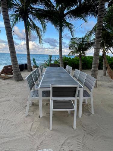 a table and chairs on a beach with palm trees at Angelina 28 Beachfront and Family Apartments - Modern and Relaxing Long Stays - 20 min from Cancun Airport in Puerto Morelos