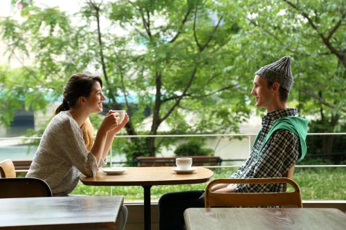 a man and a woman sitting at a table drinking coffee at Hotel Flex in Hiroshima