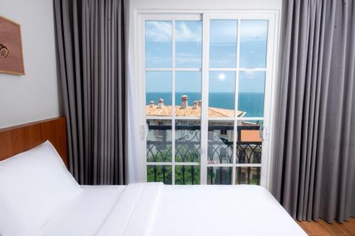 a bedroom with a large window with a view of the ocean at Great Hotel Phú Quốc in Phu Quoc