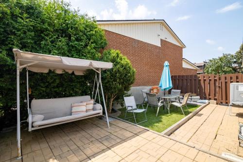 a patio with an umbrella and a table and chairs at Maison Spacieuse 3CH Piscine et Jardin Privé in Longueuil